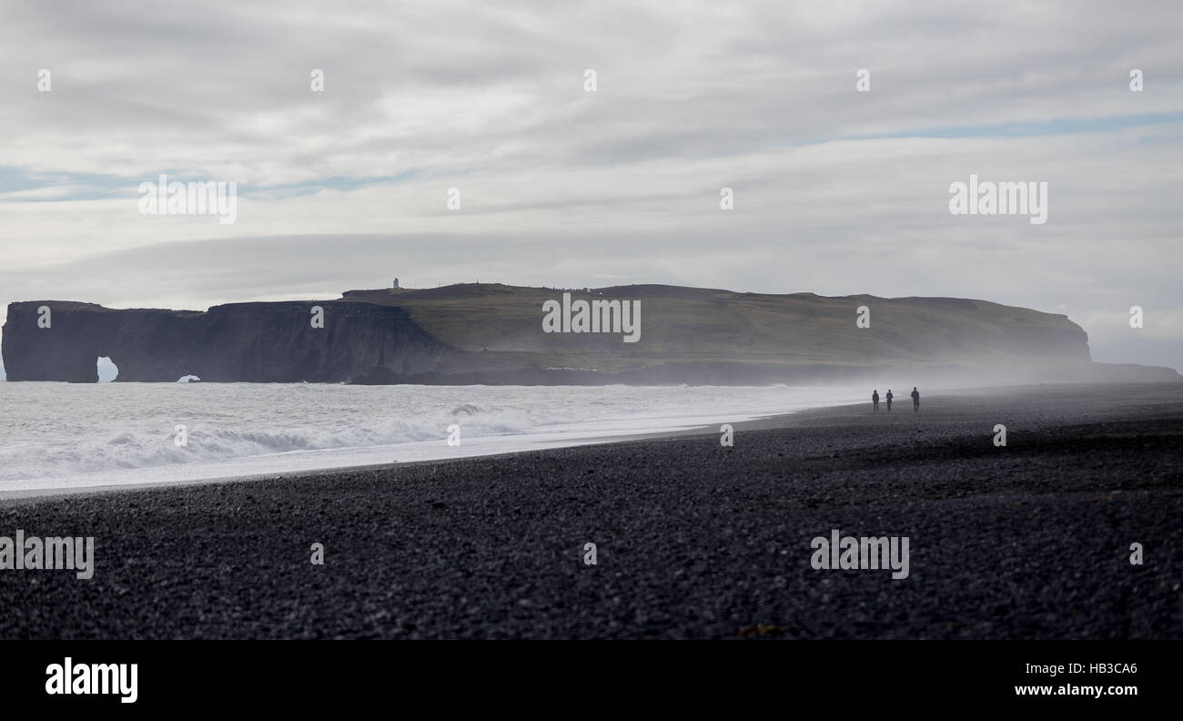 3 personnes marchant sur la plage de sable noir en Islande Banque D'Images