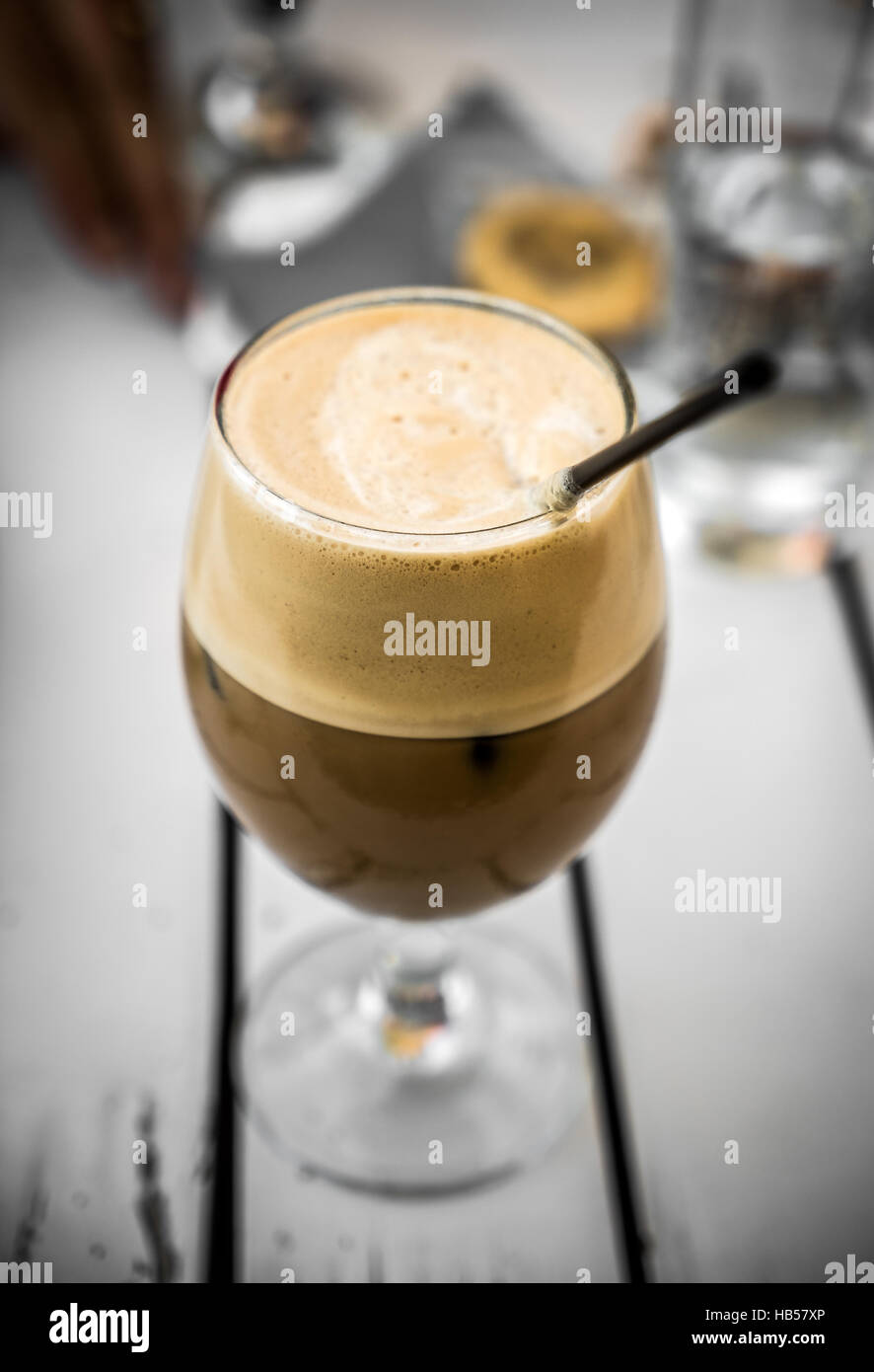 Freddo Cappuccino café en verre avec paille, sur une table en bois blanc Banque D'Images