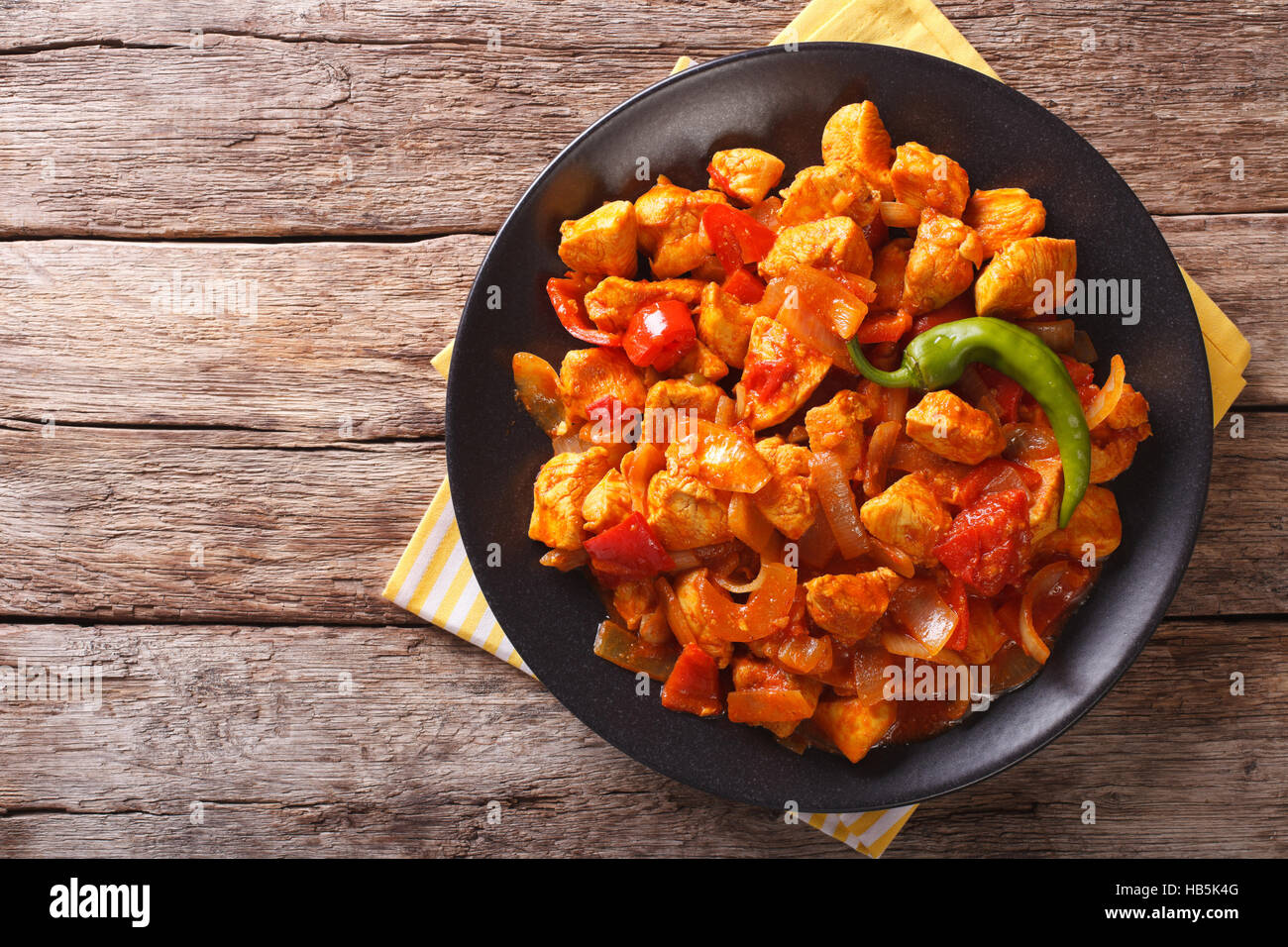 Poulet au curry indien populaire Jalfrezi, sautés, avec des épices, avec une sauce tomate et poivrons rouge et vert du dessus horizontale. Banque D'Images