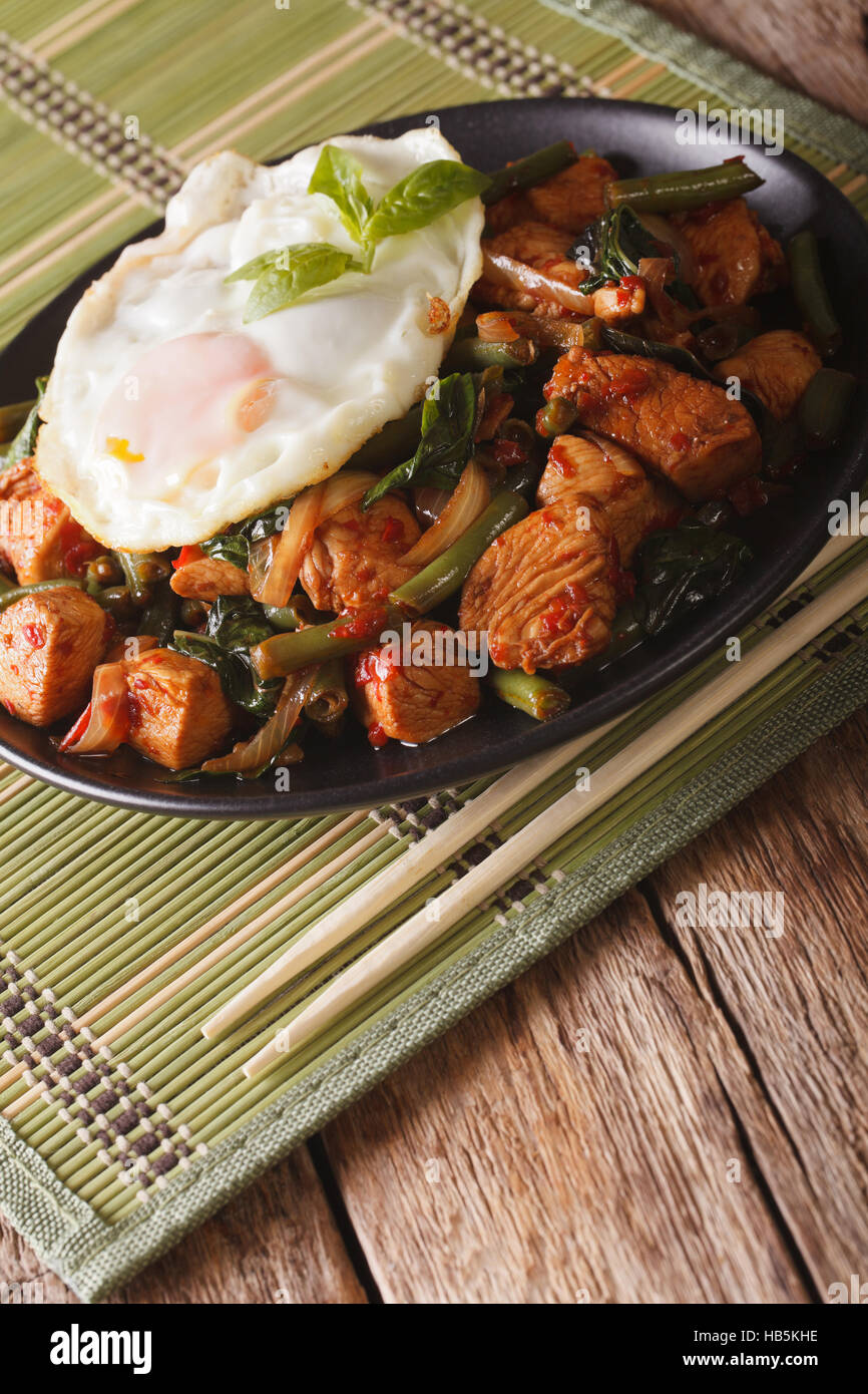 La cuisine thaïlandaise poulet, haricots verts et un œuf frit sur une plaque verticale close-up Banque D'Images