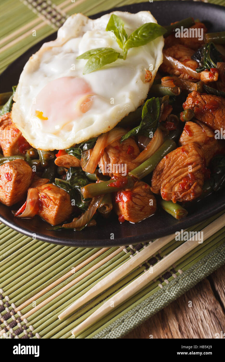 Gai Pad Thaï Krapow poulet, haricots verts et un œuf frit sur une plaque verticale close-up Banque D'Images