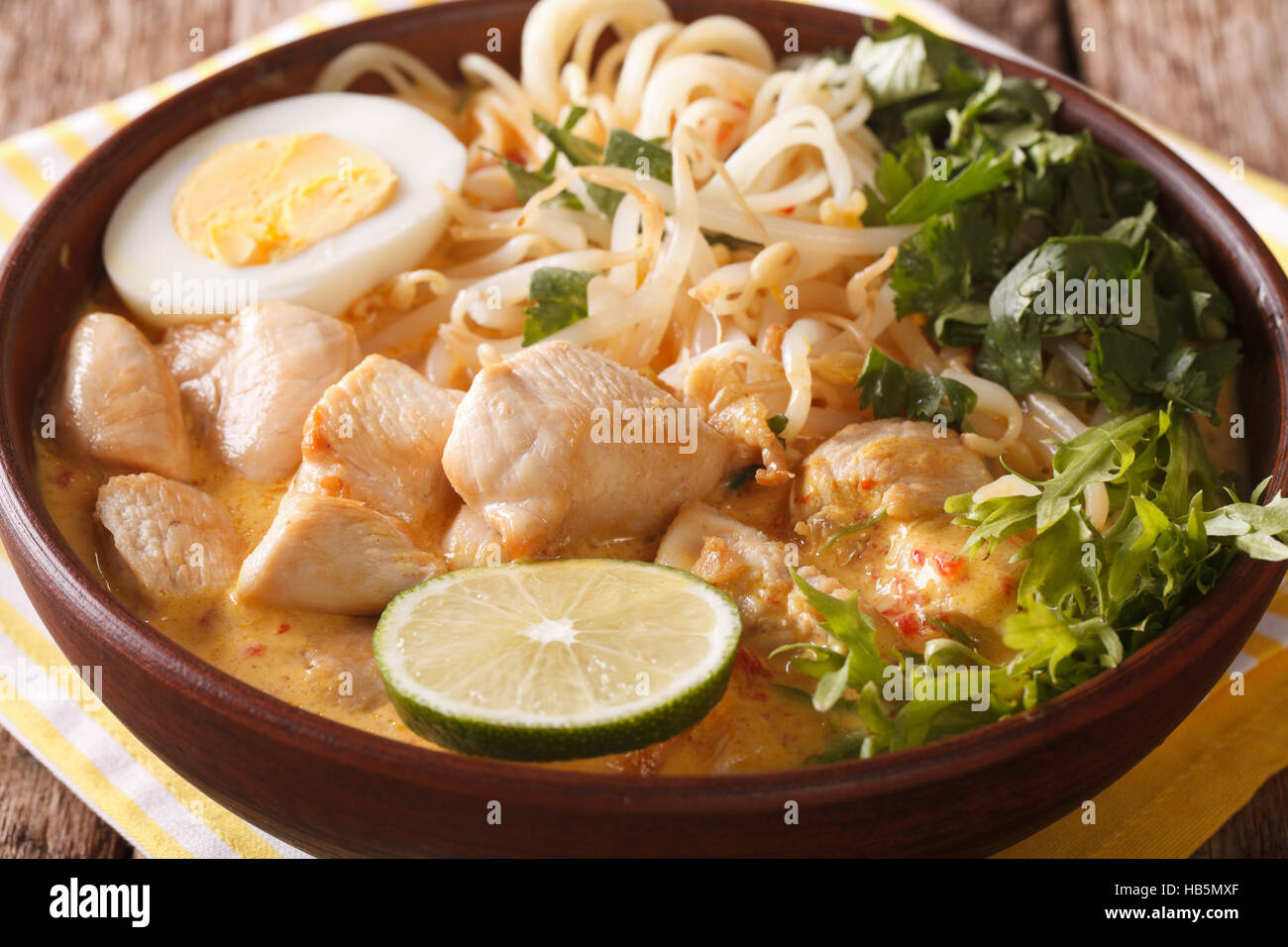 Soupe Laksa au poulet, oeuf, pâtes de riz, de germes de soja et la coriandre dans un bol sur la table horizontale. Banque D'Images