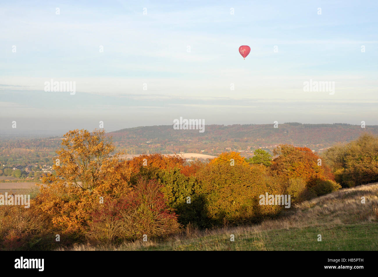 Chiltern Hills - Couleurs d'automne dans les arbres - Ciel bleu moucheté de nuages - red hot air balloon flottant doucement sur les collines Banque D'Images