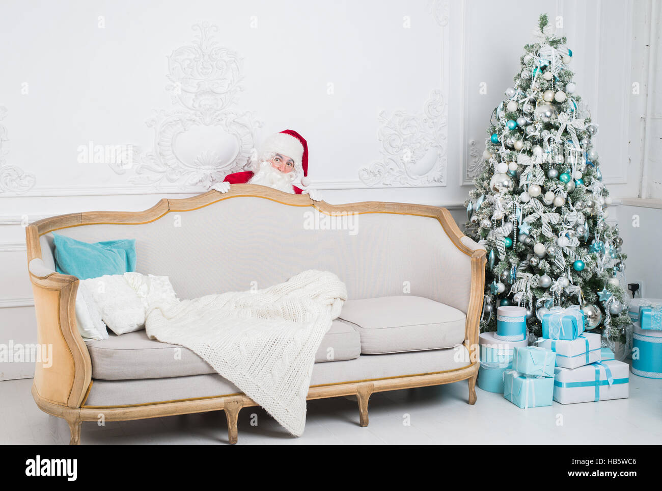 Santa Claus se cacher derrière un canapé plus home intérieur Banque D'Images