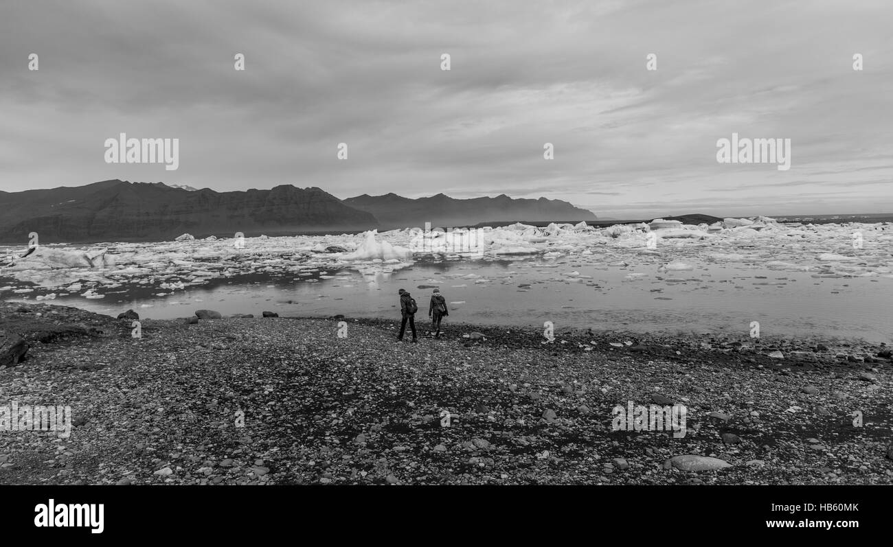 Deux personnes marchant près du glacier Lagoon dans le sud de l'Islande en noir et blanc Banque D'Images