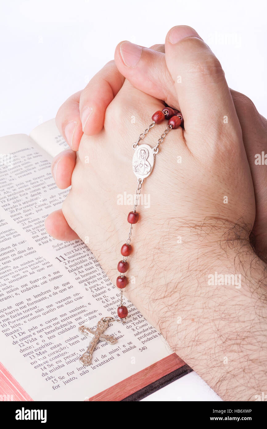Les mains des hommes en prière fermé tenant un rosaire sur une vieille Bible. Banque D'Images