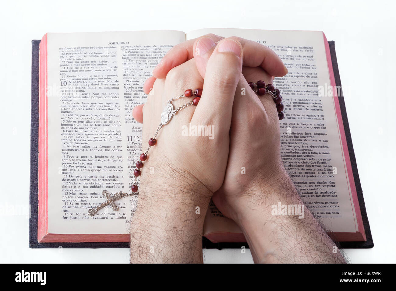 Les mains des hommes en prière fermé tenant un rosaire sur une vieille Bible. Banque D'Images