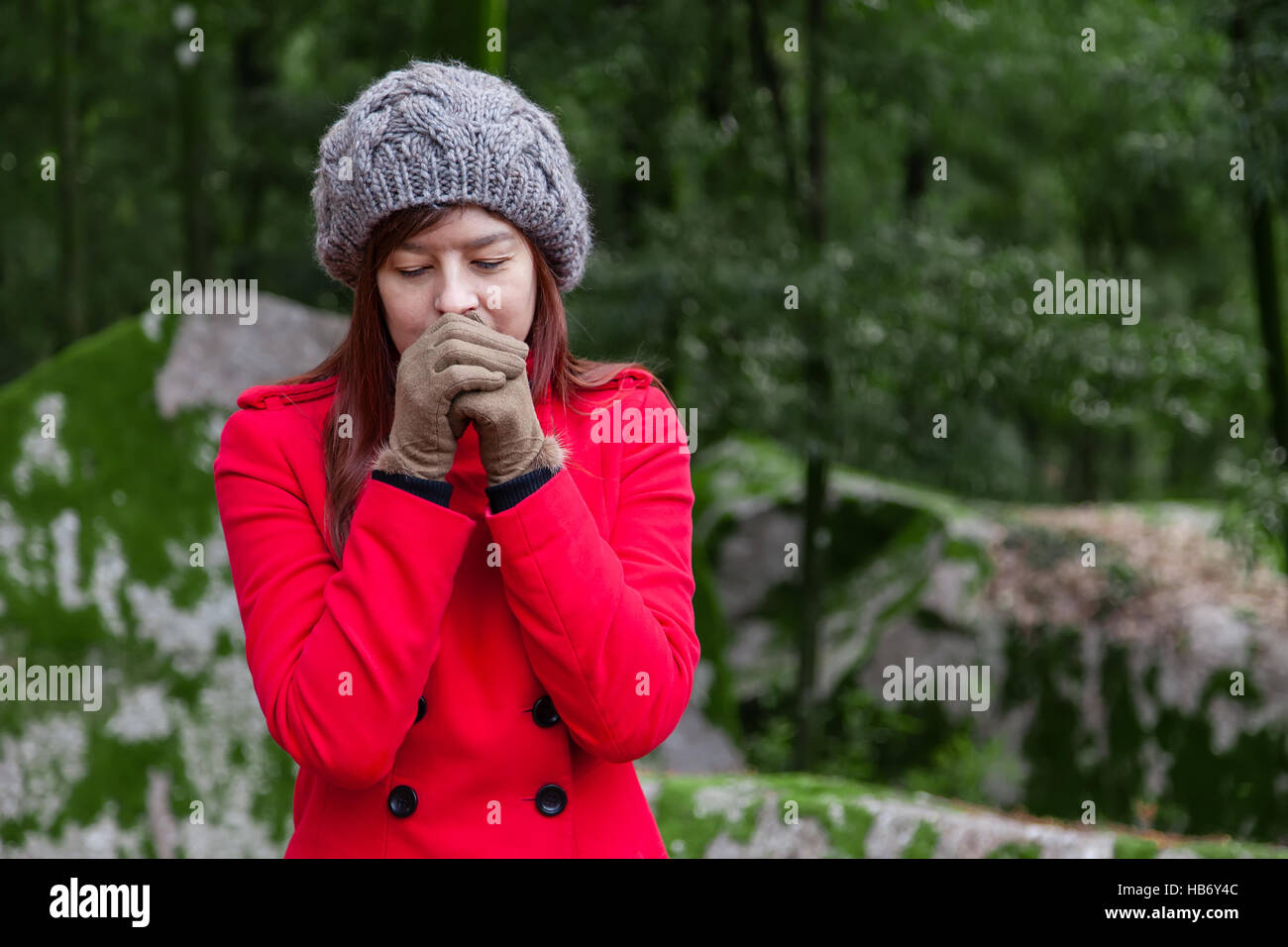 Jeune femme tremblant de froid sur une forêt portant un manteau, un bonnet et des gants pendant l'hiver Banque D'Images