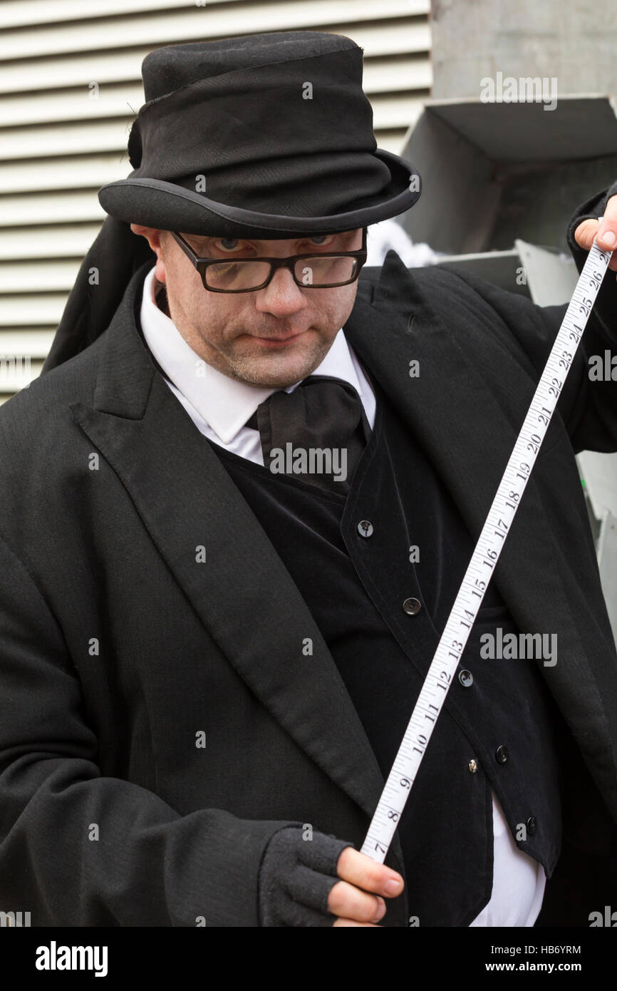 Undertaker avec ruban de mesure mesure jusqu'à la fête de Noël victorien à Portsmouth, Hampshire, England UK en Novembre Banque D'Images