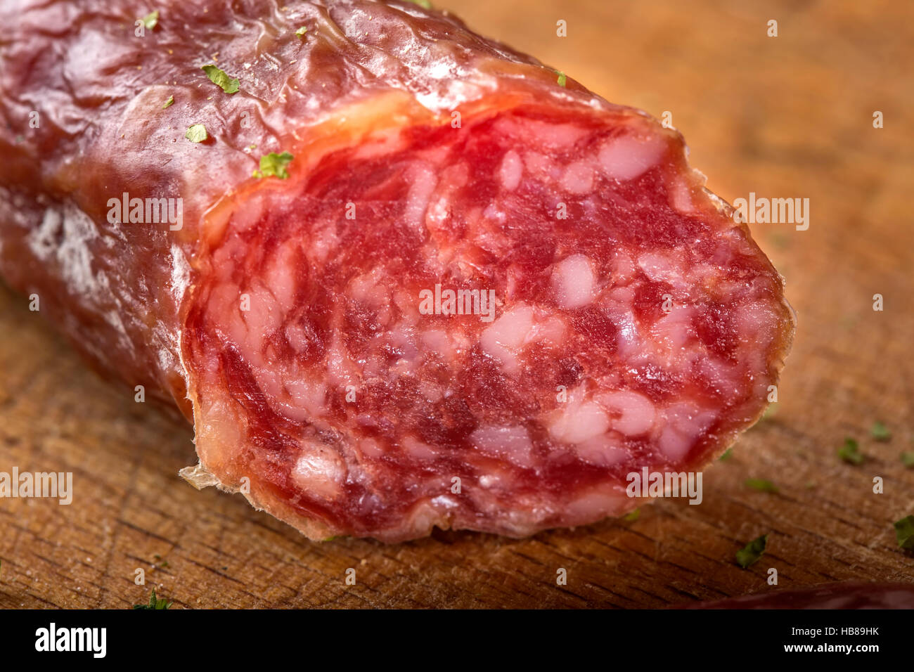 Close up of salami italien sur planche à découper en bois avec des herbes Banque D'Images