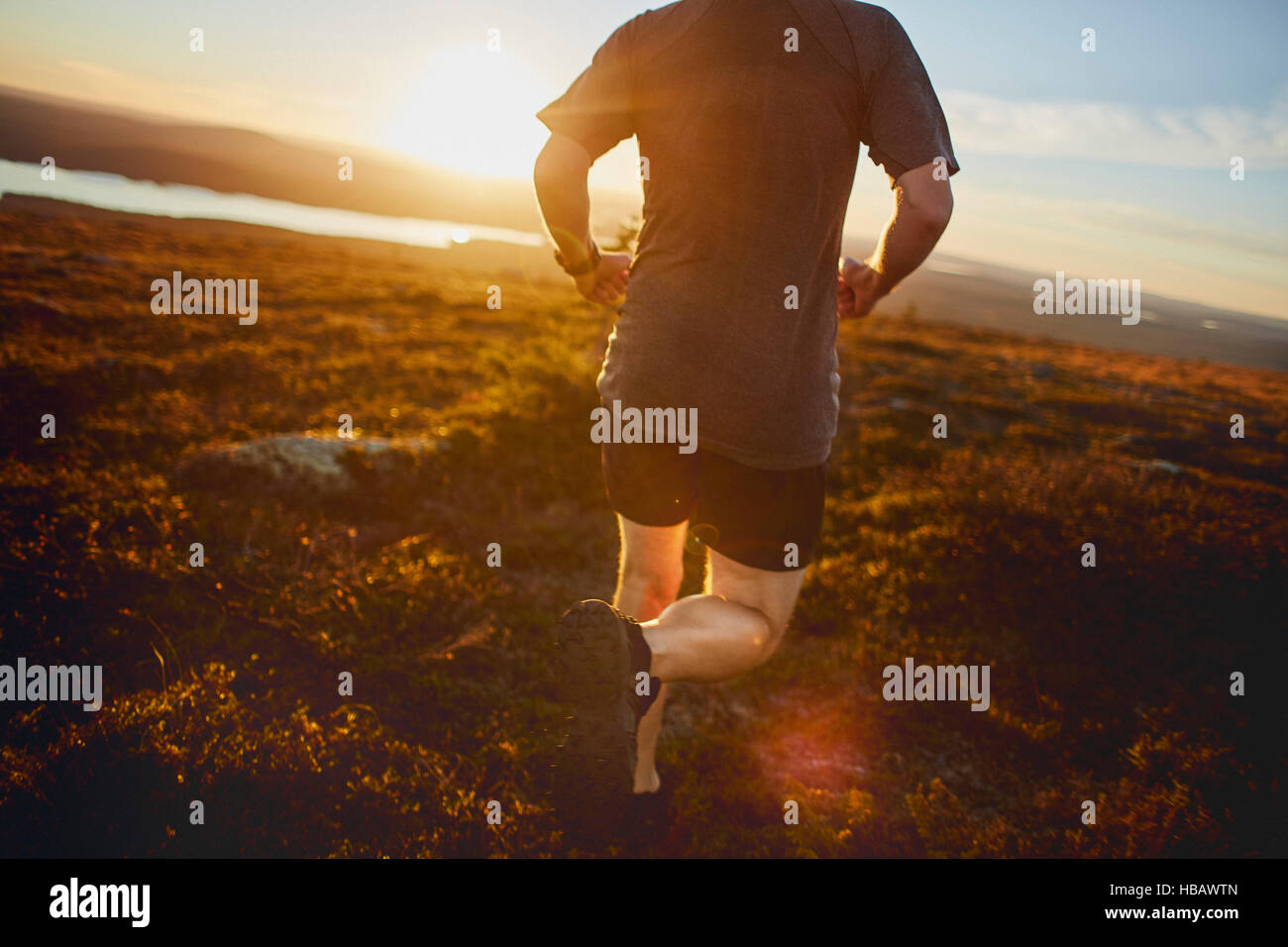 Homme qui court sur la falaise au coucher du soleil, Keimiotunturi, Laponie, Finlande Banque D'Images