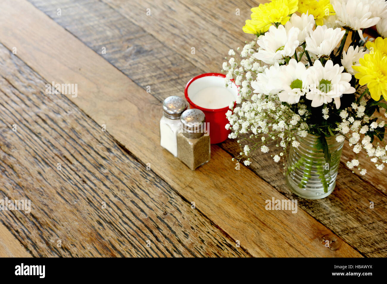 Table en bois dans un café avec arrangement floral et Sel & poivre Banque D'Images