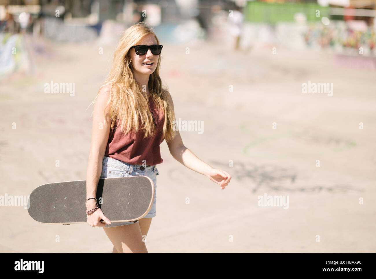 Young woman walking with skateboard en skatepark Banque D'Images