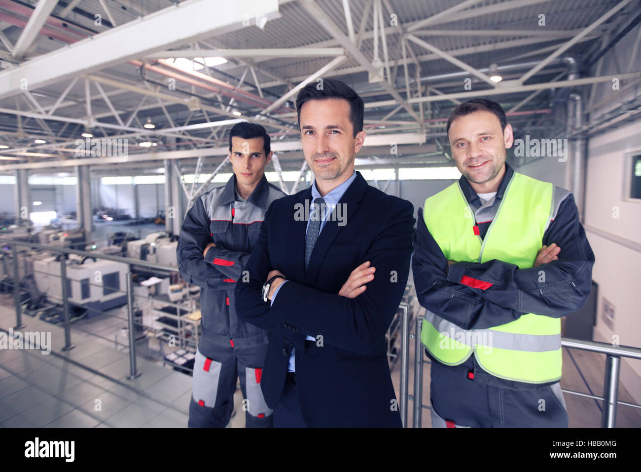 Équipe de manager et deux travailleurs en usine CNC Banque D'Images