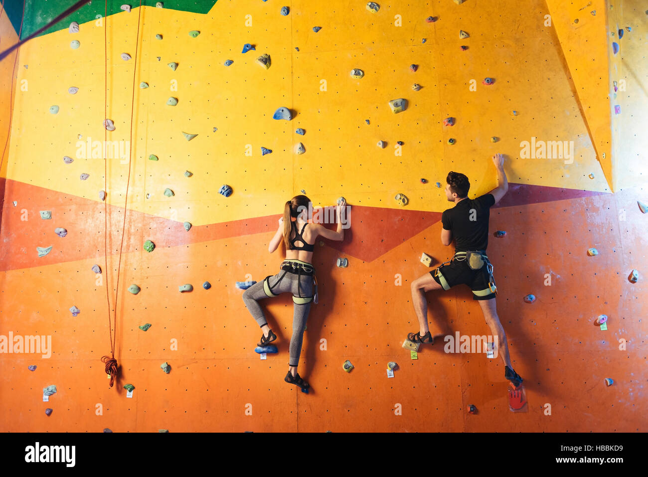 Young man and woman climbing up the wall Banque D'Images