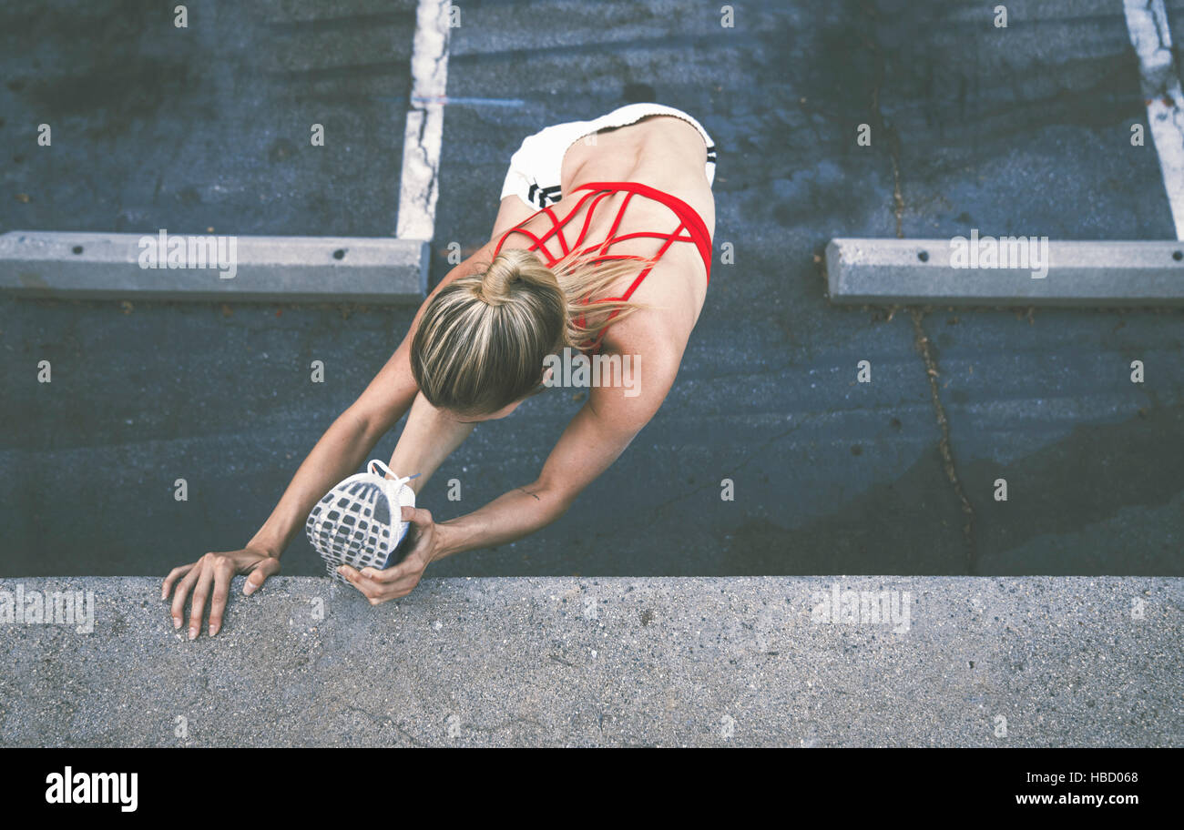 Young woman stretching contre wall outdoors Banque D'Images