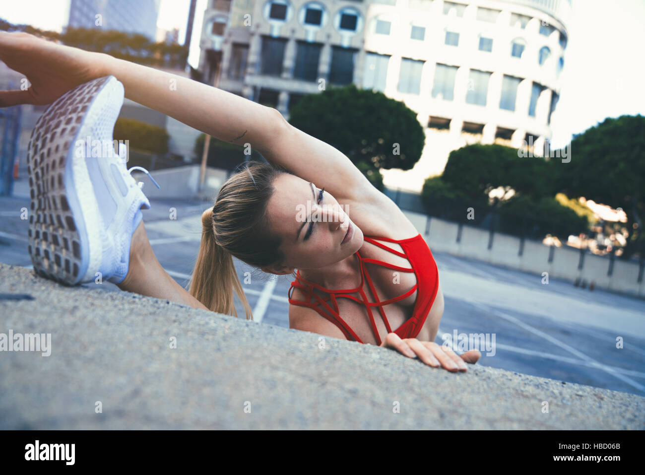 Young woman stretching contre wall outdoors Banque D'Images