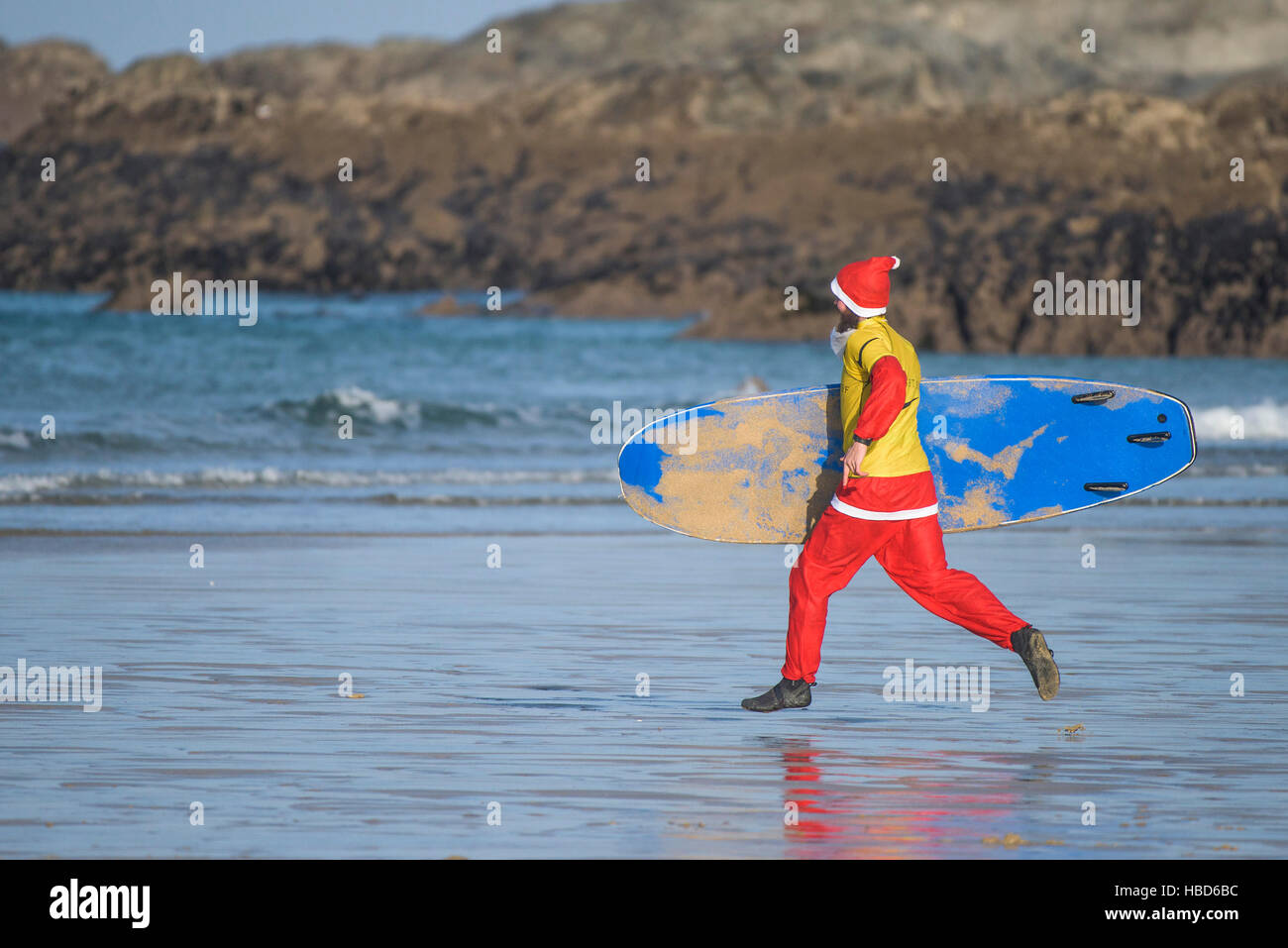 Un surf Santa s'exécutant dans une course au début de la collecte de fonds Santa Surf sur une concurrence très frileux dans la plage de Fistral Newquay, Cornwall. Banque D'Images