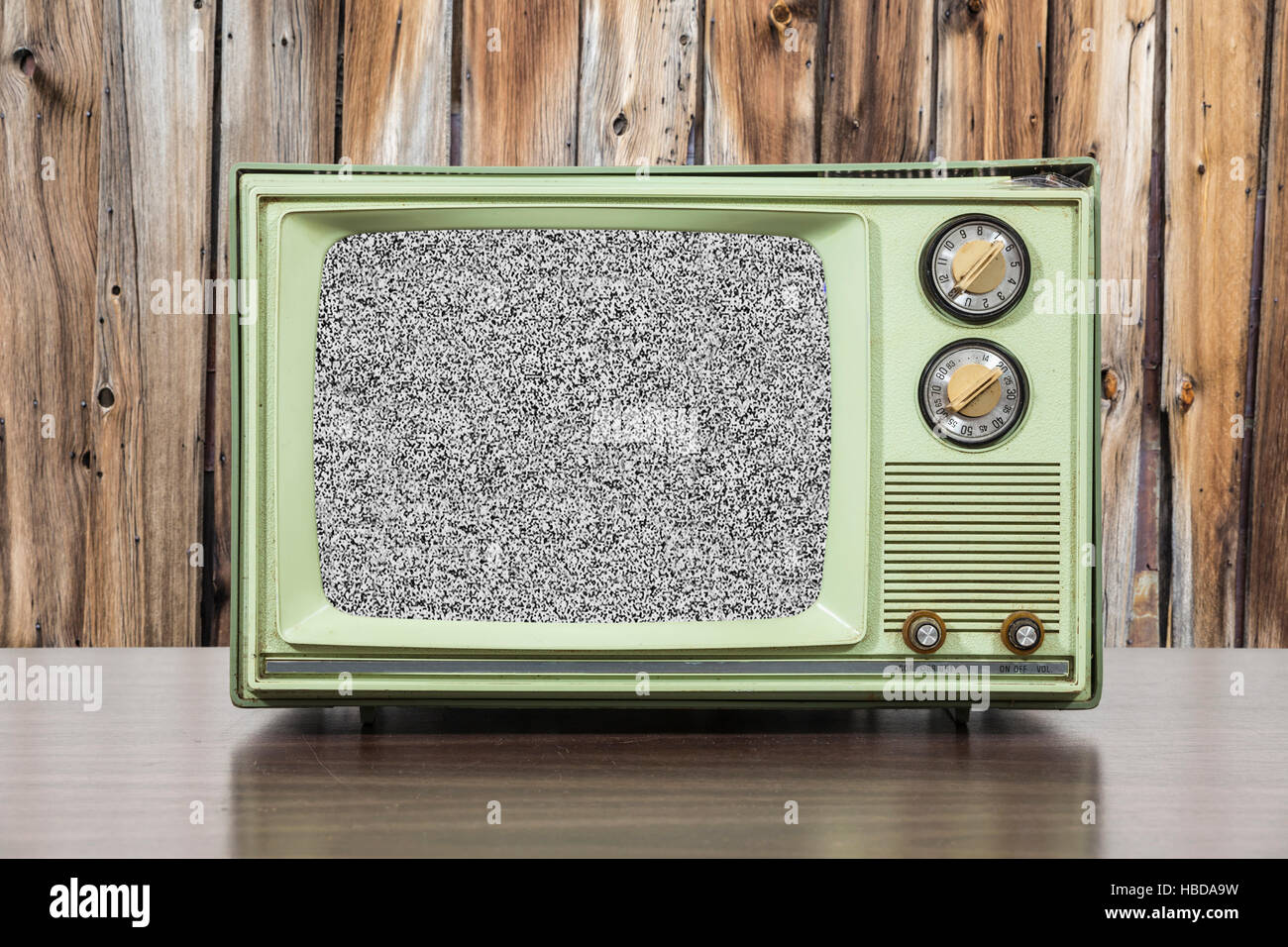 Grungy green vintage téléviseur avec écran statique et mur en bois. Banque D'Images