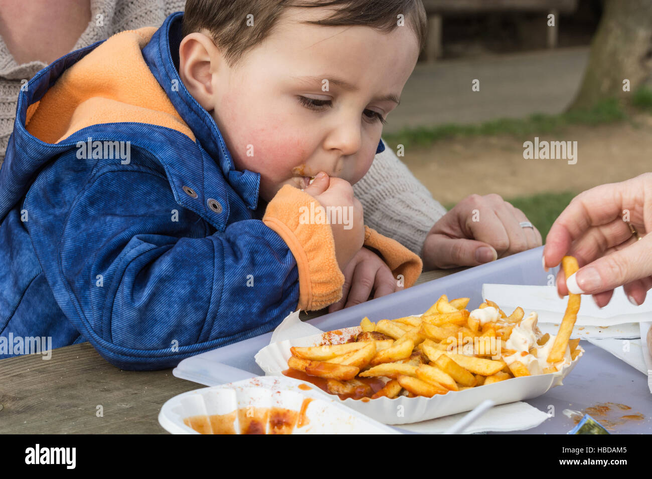 Enfant mange des saucisses avec des frites Banque D'Images