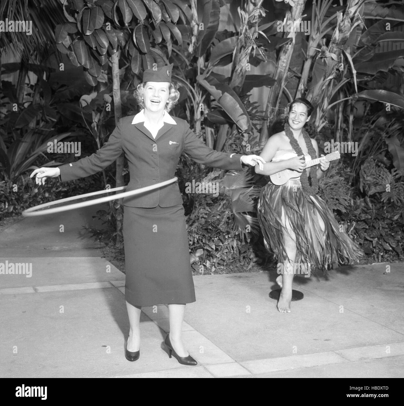 Canadian Pacific Airlines stewardess Helen Phillips de Vancouver fait l'essai d'un hula hoop, accompagné de hula girl Jackie Akeo de Honolulu. Helen, qui vole régulièrement la route de l'ACP du Pacifique Sud, le hula hoop a même envahi les terres de l'original de la danse hula. Banque D'Images