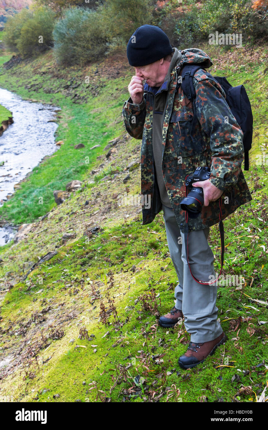 Un photographe de la faune de décider d'aller sur une pente river bank, faire une évaluation des risques. Banque D'Images