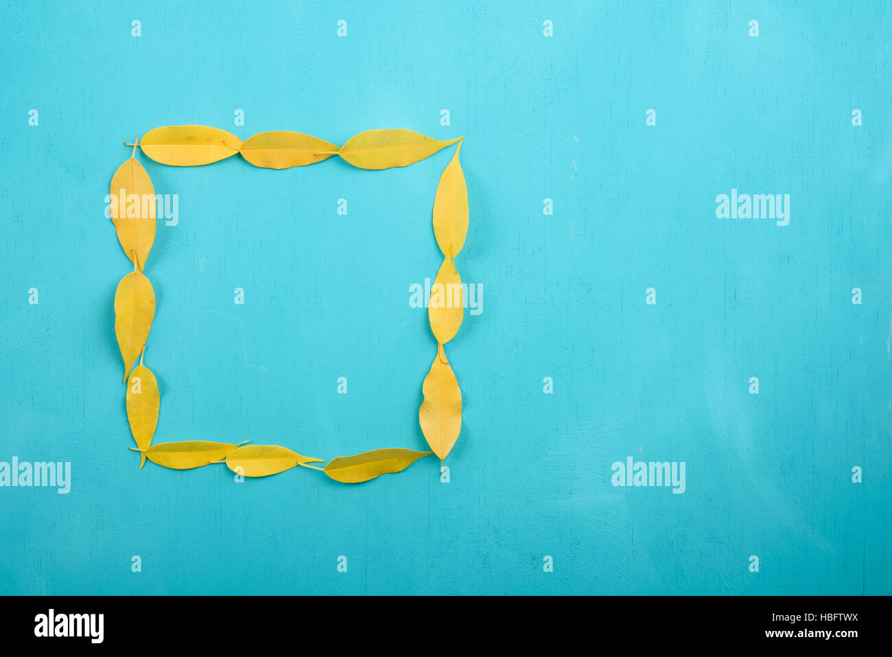 Feuilles d'automne jaune forme carré Turquoise sur table en bois Banque D'Images