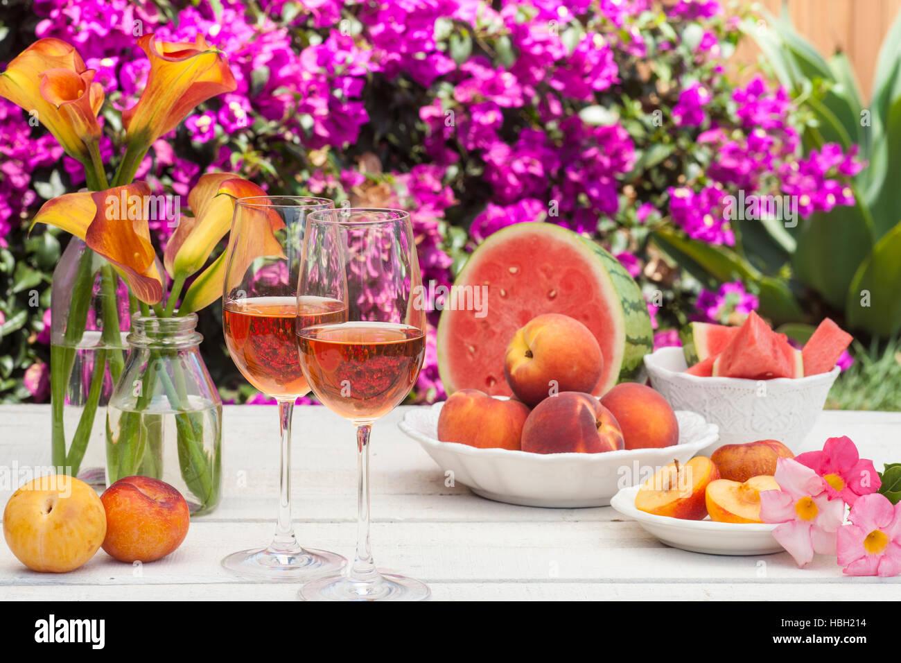Verres de vin rose, pêches, prunes et melon à un pique-nique dans l'été Banque D'Images