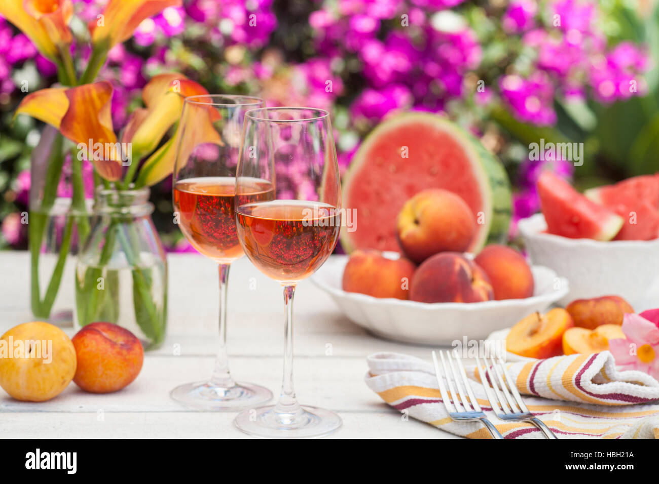 Verres de vin rose, pêches, prunes et melon à un pique-nique dans l'été Banque D'Images