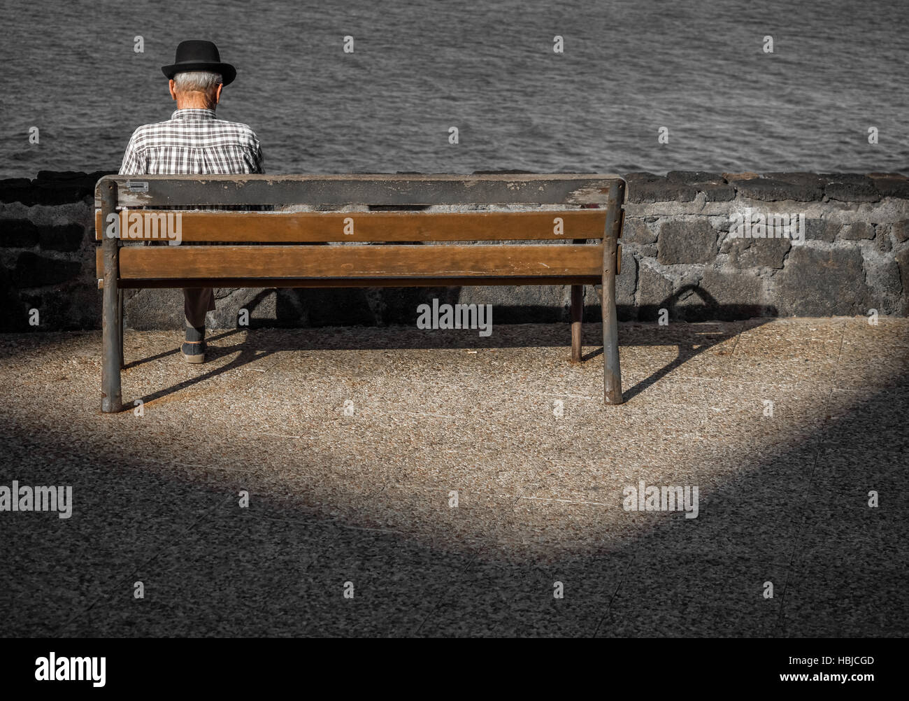 Vieil homme assis sur un banc en bois Banque D'Images