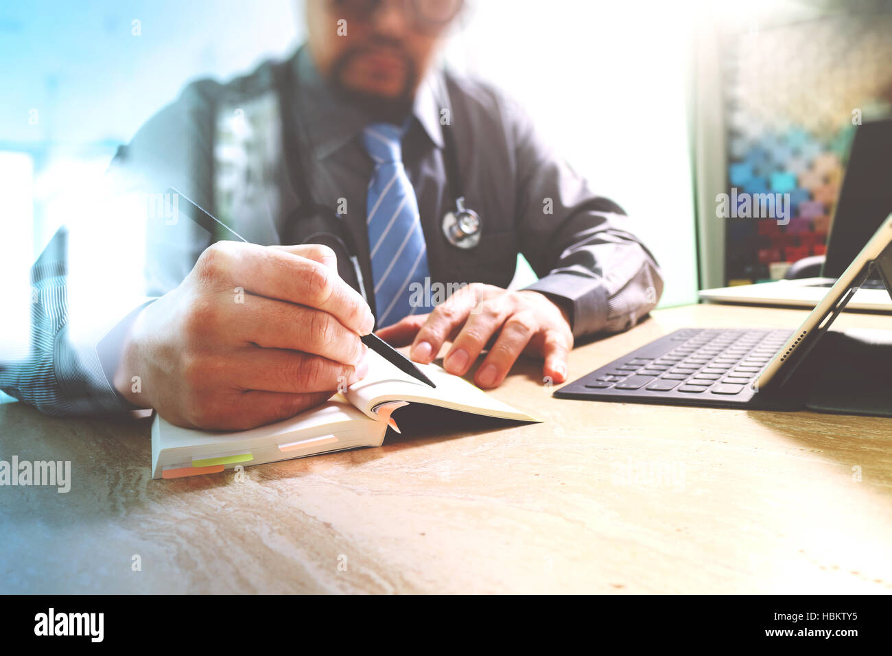Médecin écrit sur ordinateur portable et tablette avec clavier numérique d'ordinateur portable sur le bureau en marbre,effet sun flare Banque D'Images