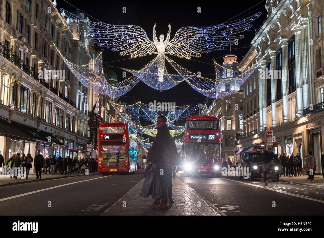 Londres - le 4 décembre 2016 : un piéton s'arrête dans la médiane de la circulation en vertu de l'allumage des anges de Noël scintillantes Regent Street. Banque D'Images