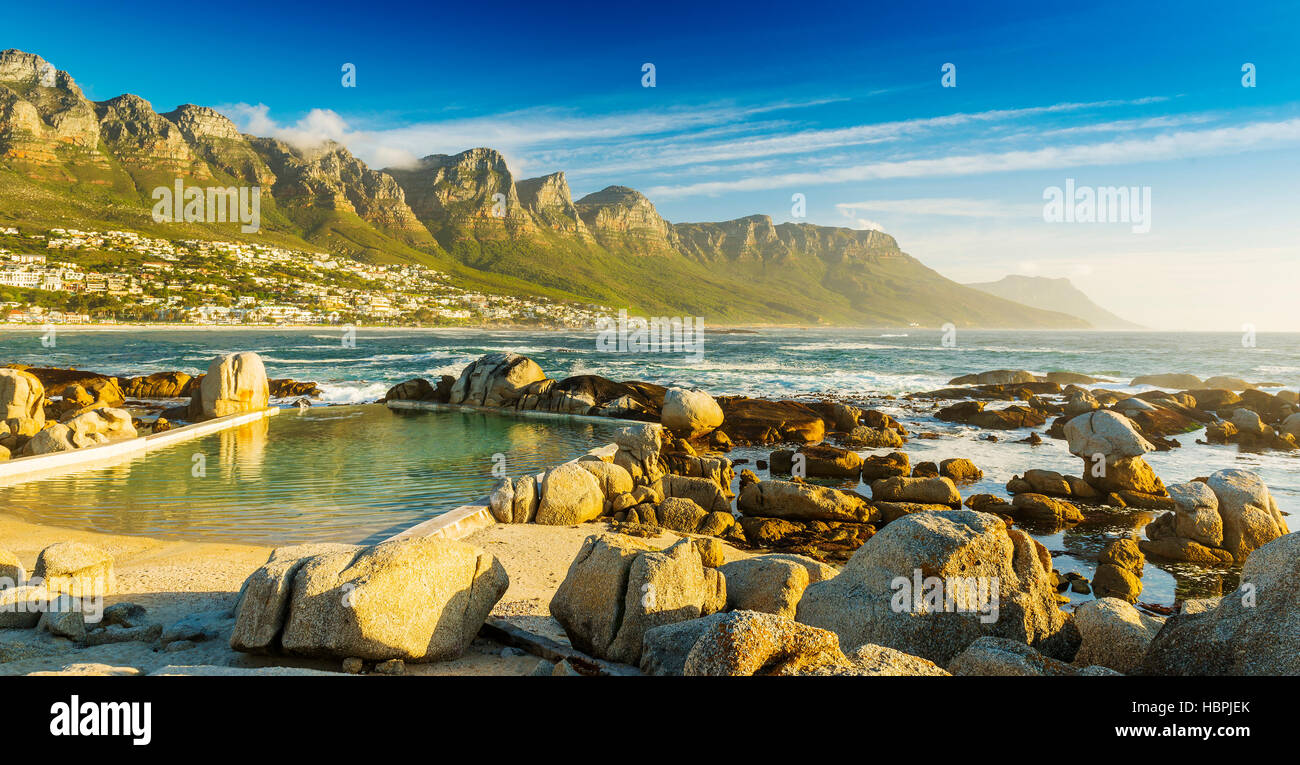 Camps Bay Ocean piscine au coucher du soleil avec la ville et les montagnes derrière Banque D'Images