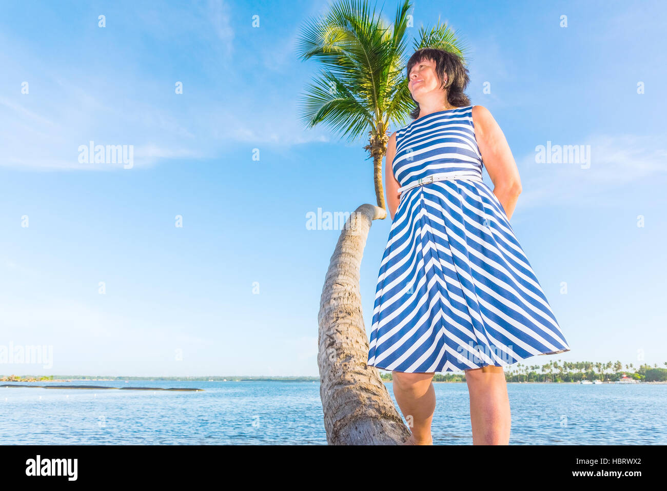 Femme d'âge moyen brunette on a palm tree Banque D'Images