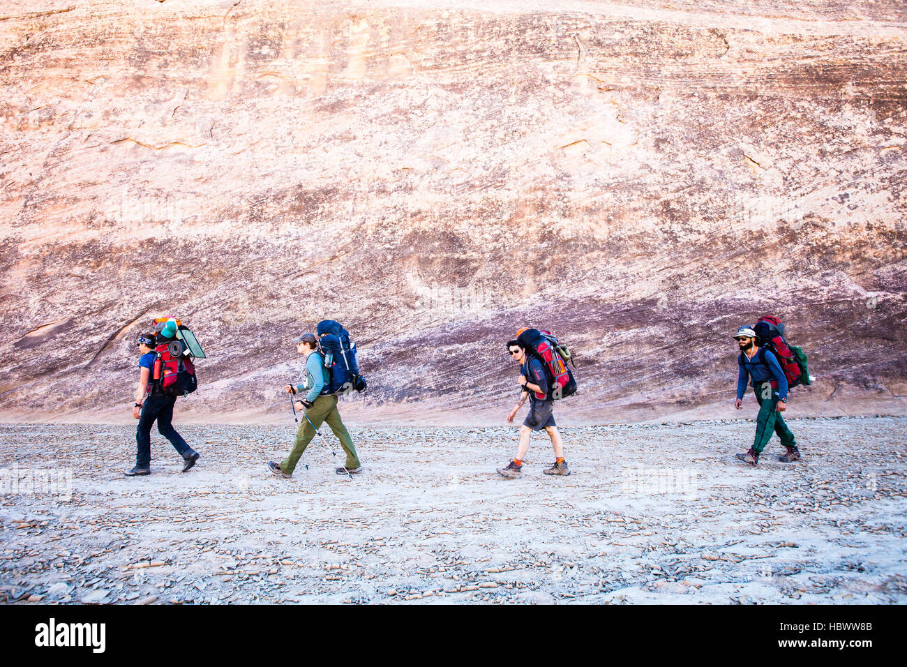 Un groupe de jeunes hommes backpacking à travers un lavage à sec dans les canyons de l'Utah Banque D'Images