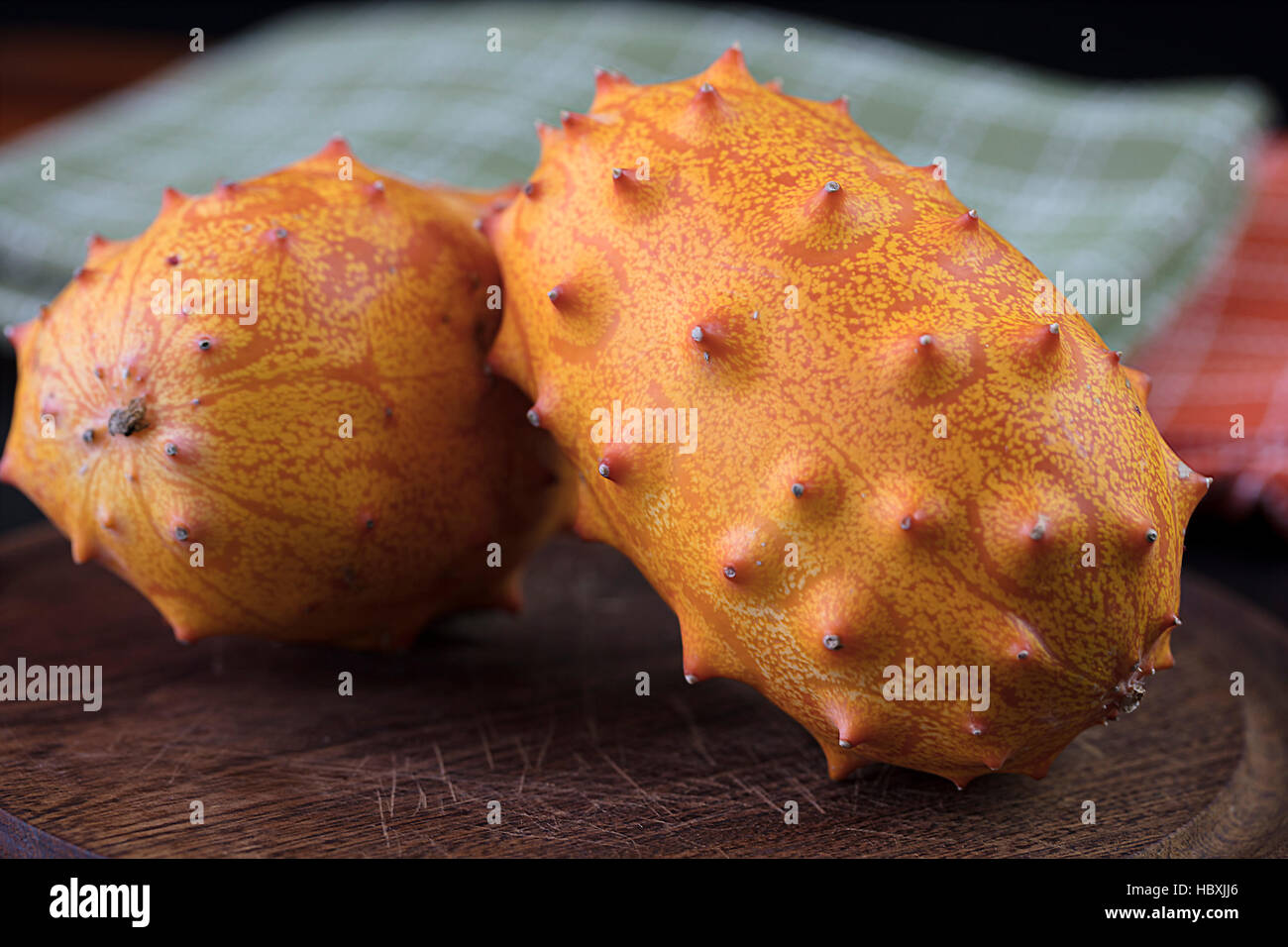 Deux Fruits Kiwano orange et vert situé sur un dessus de table avec la peau épineuse Banque D'Images