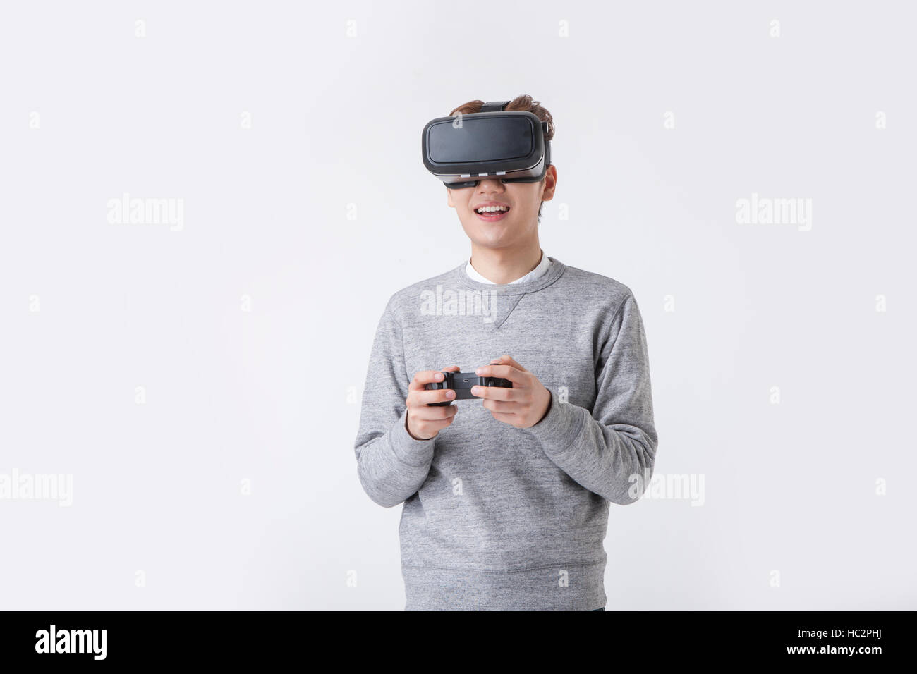 Young smiling Korean man enjoying jeu de réalité virtuelle Banque D'Images