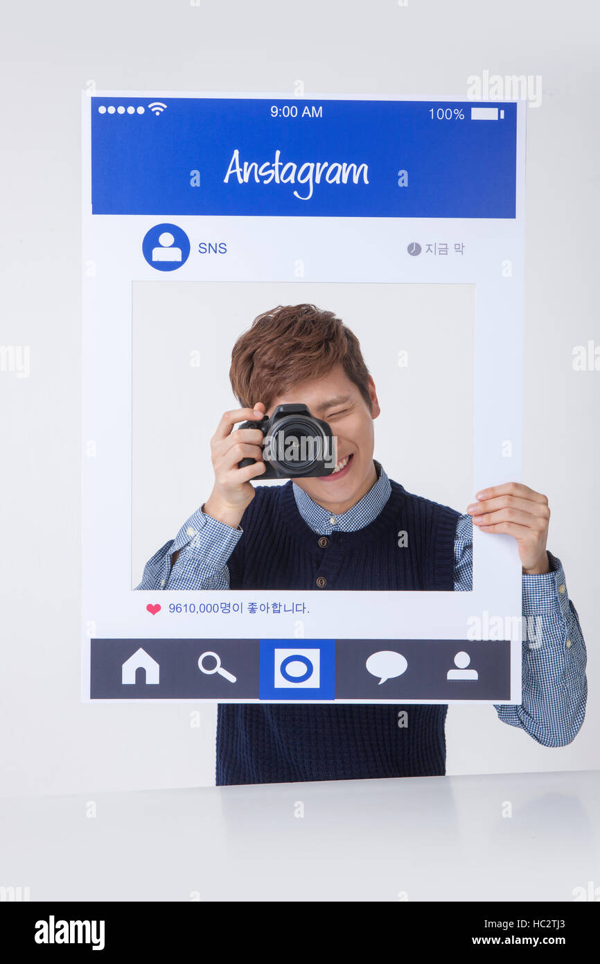 Portrait of young smiling homme posant avec un appareil photo sur SNS Banque D'Images