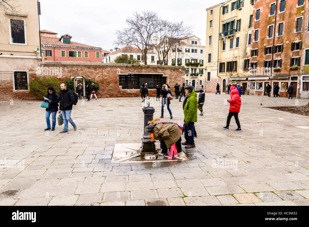 Une vieille femme d'une fontaine d'eau potable sur la rue en Campo del Ghetto, Venise, Italie Banque D'Images