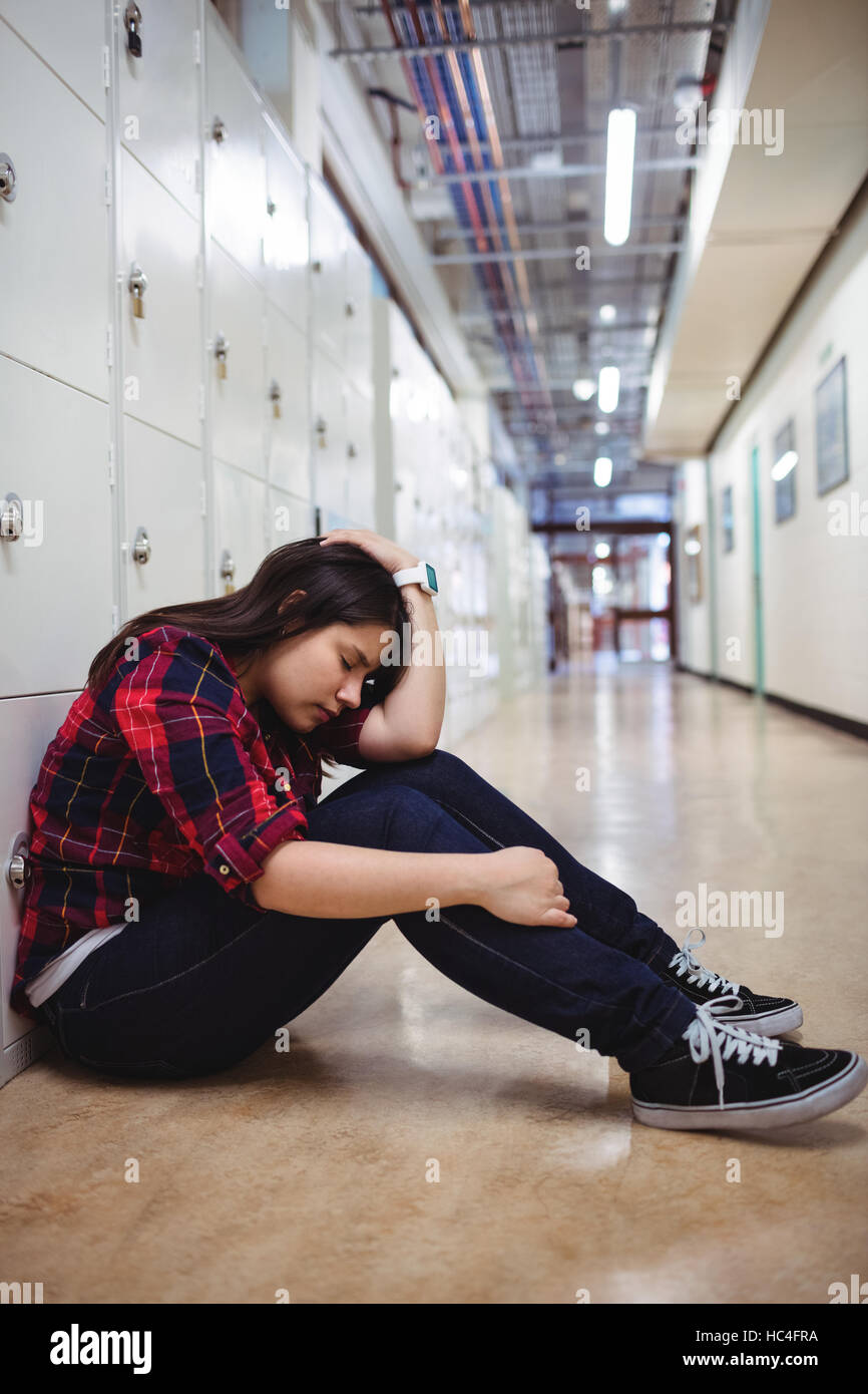 Déprimé female student sitting in locker room Banque D'Images