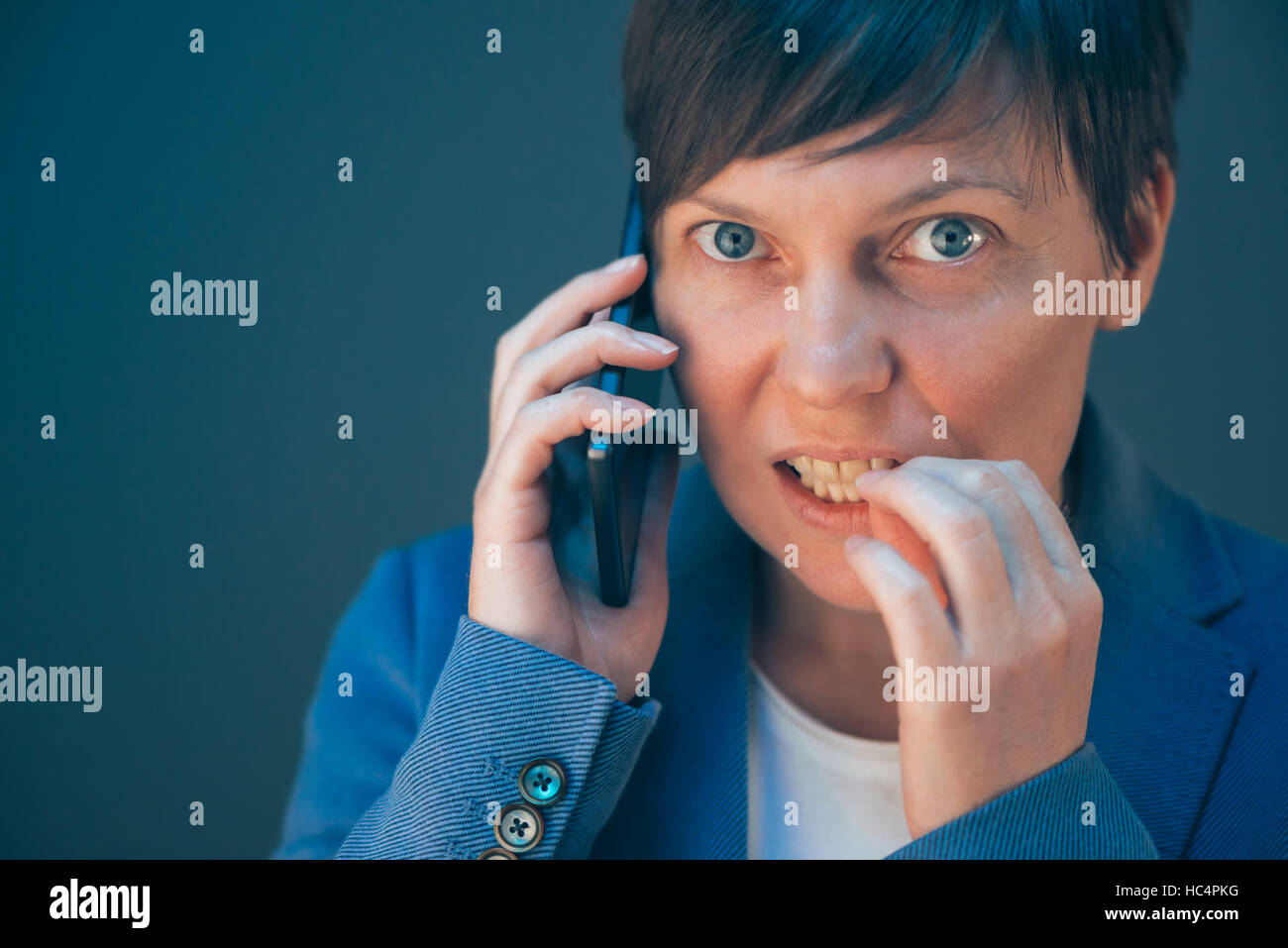 Femme d'nerveux ongles piqûres au cours de conversation téléphonique le téléphone mobile Banque D'Images