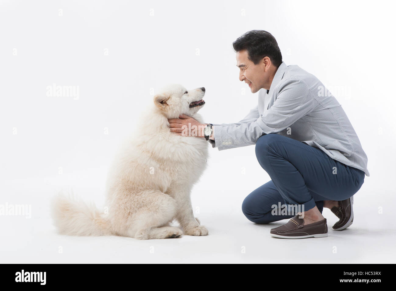 Vue latérale du smiling middle aged man petting son chien face à face Banque D'Images