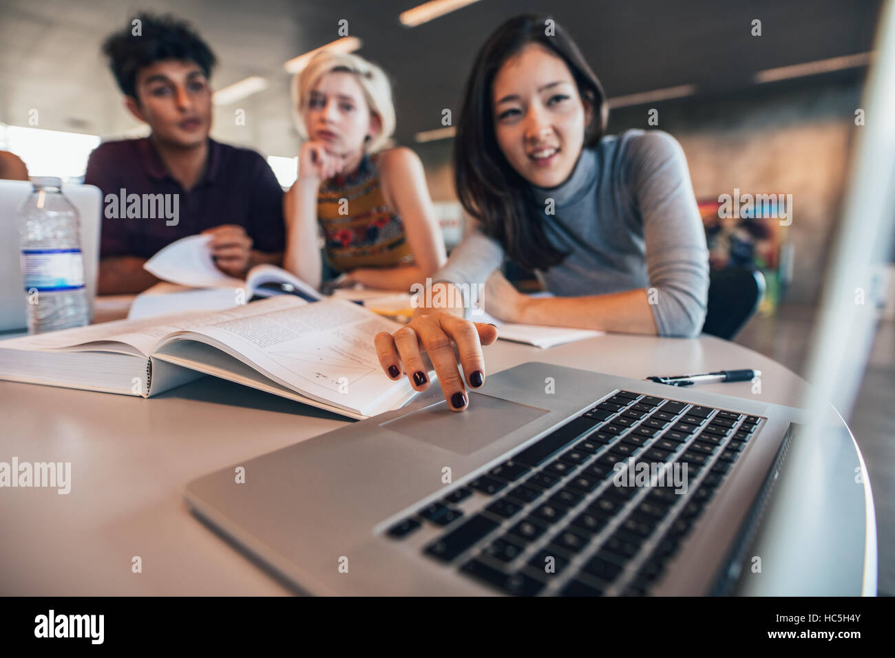 Les étudiants de l'université en utilisant un ordinateur portable dans une bibliothèque. Jeune homme et femme d'étudier ensemble. Banque D'Images