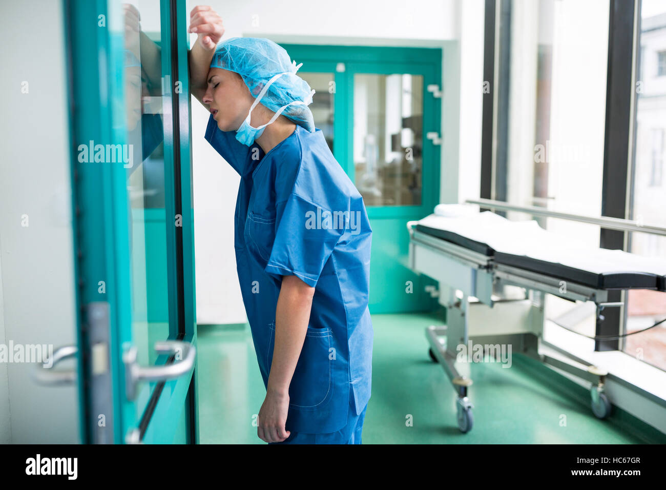 Chirurgien triste appuyé contre la porte en verre Banque D'Images