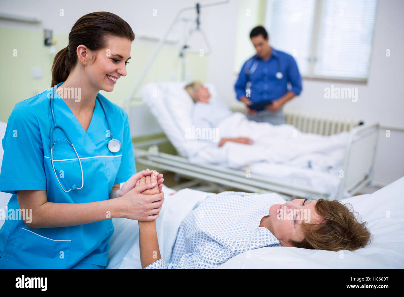 Infirmière à l'hôpital un patient consolant ward Banque D'Images