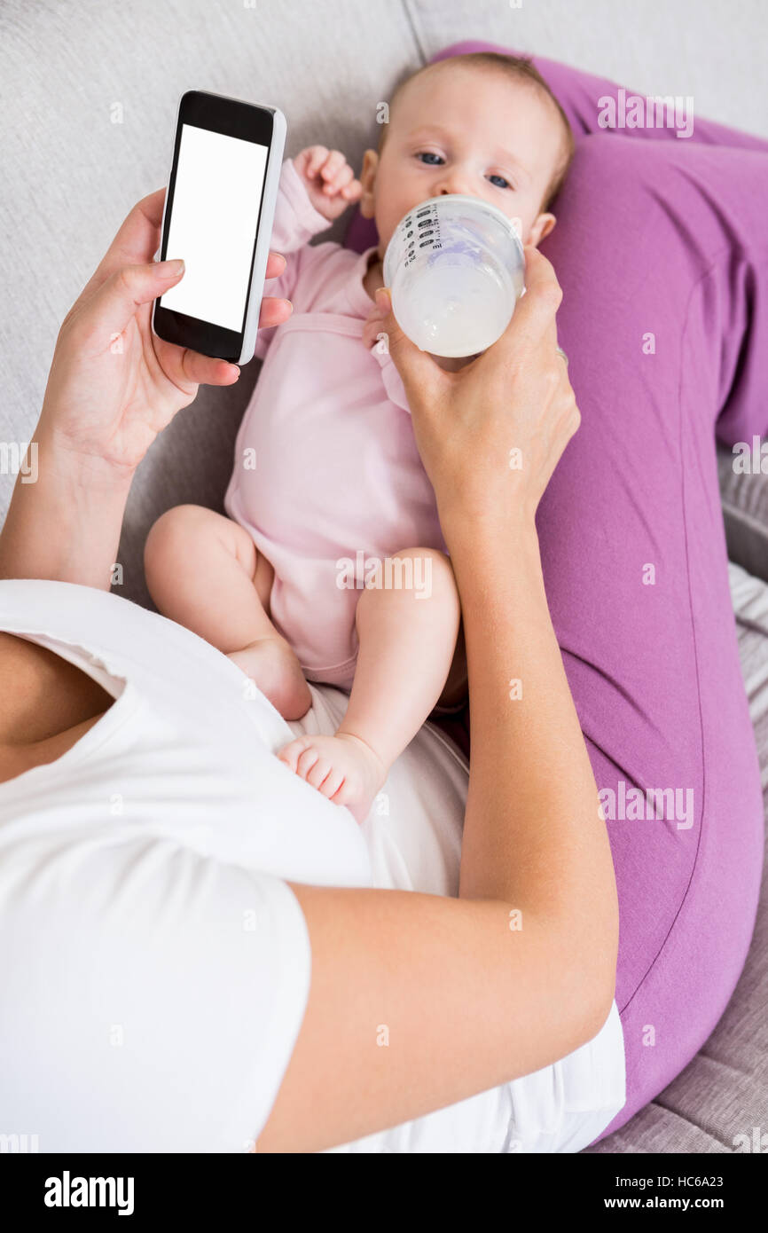 Mere A L Aide De Telephone Mobile Tout En Alimentant Son Bebe Avec Une Bouteille De Lait Photo Stock Alamy