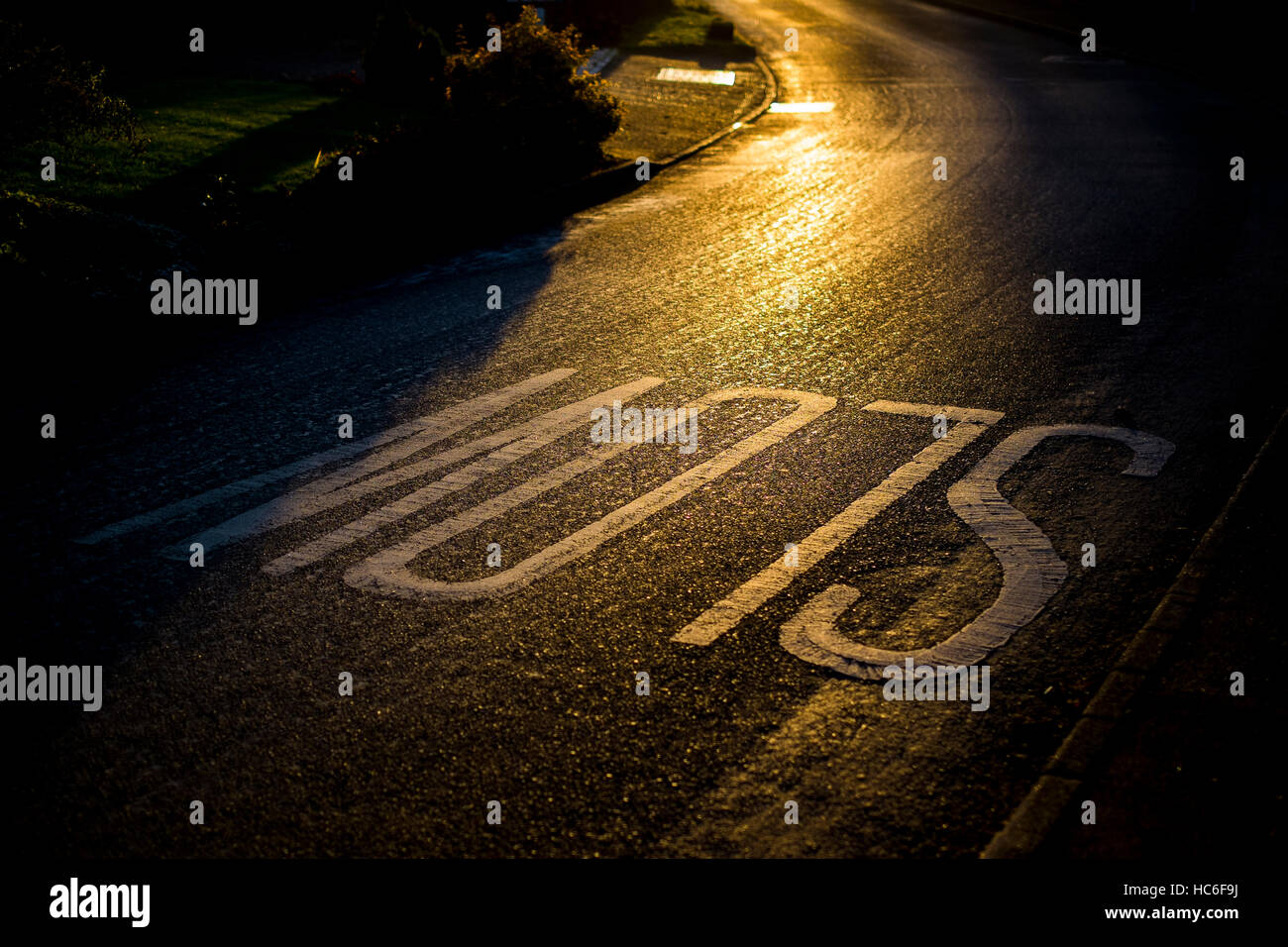 Un lent signe sur une route de village au coucher du soleil Banque D'Images