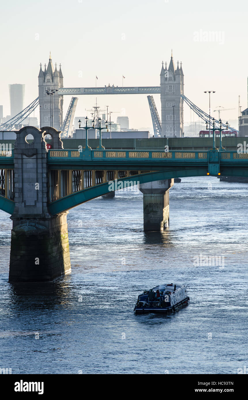 Bateau étroit sur la Tamise à Londres sous les ponts. Une vue matinale hivernale et brumeuse sur Southwark Bridge vers Tower Bridge Banque D'Images