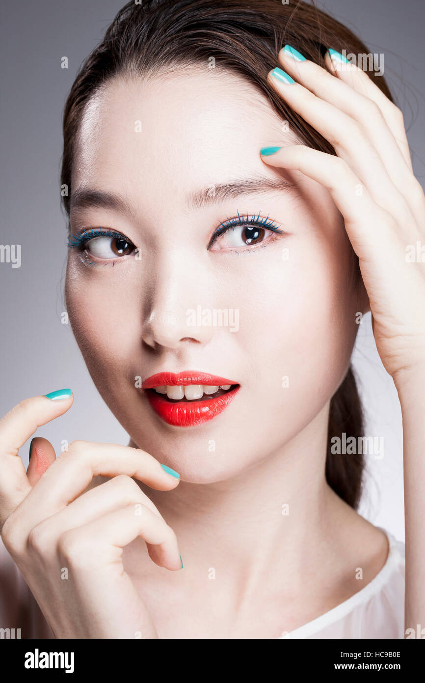 Portrait of young smiling woman with red lips coréen et les ongles bleu Banque D'Images