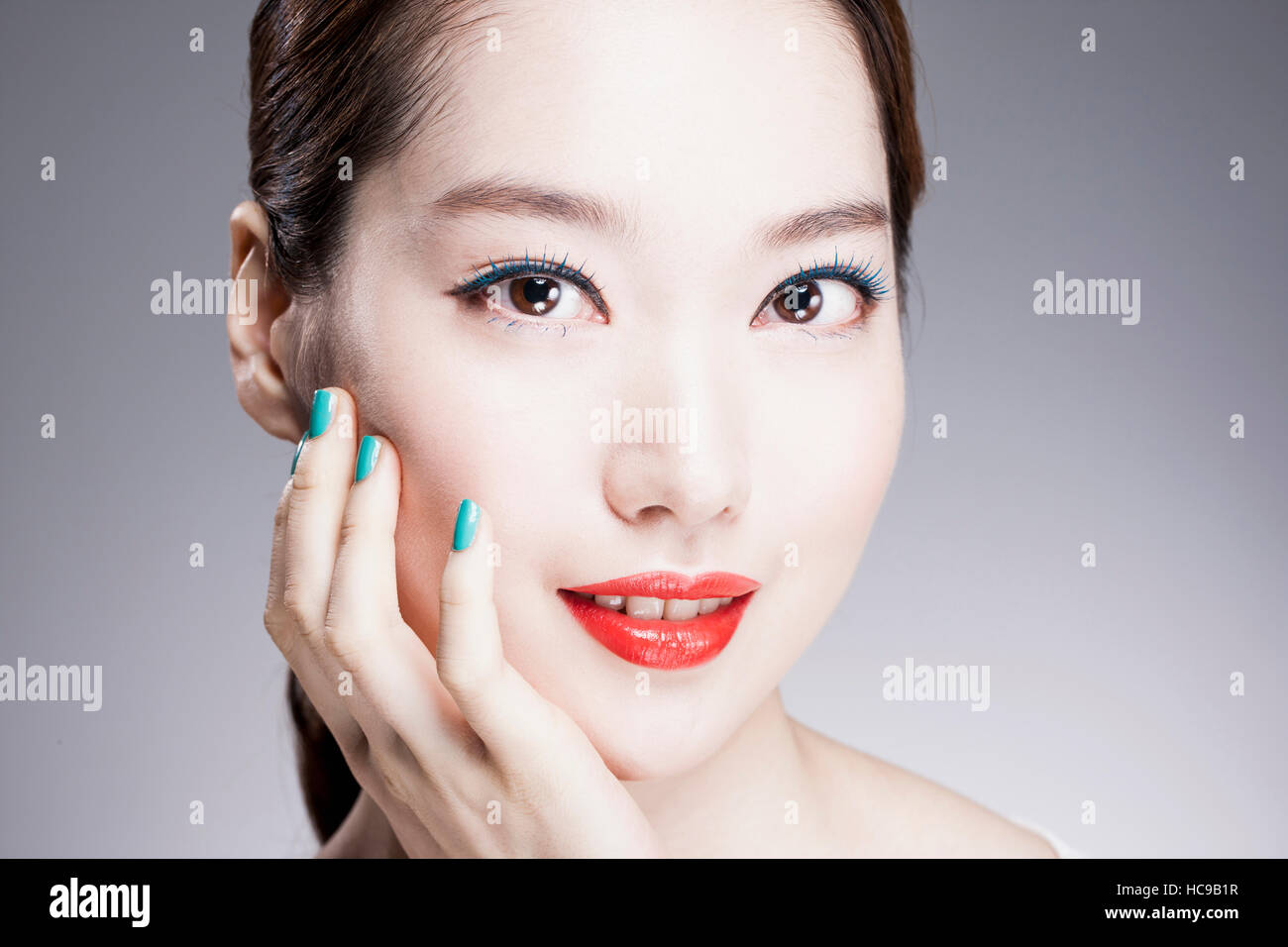 Portrait of young smiling Korean woman with red lips et blue nails Banque D'Images
